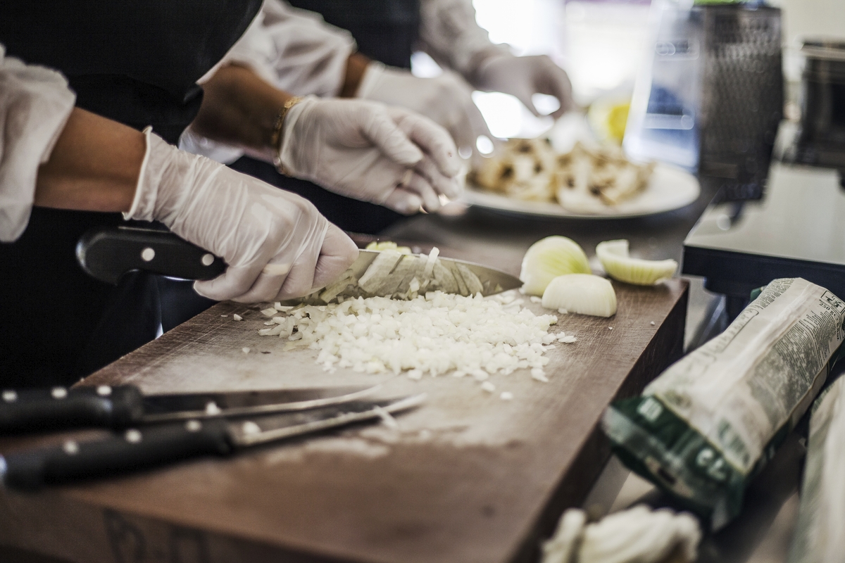 Un cuisinier qui coupe des oignons sur une planche de bois.